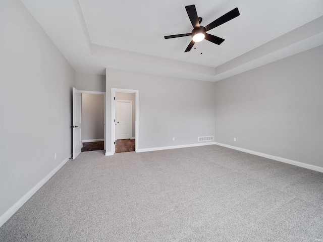 unfurnished bedroom featuring ceiling fan, a raised ceiling, and carpet floors