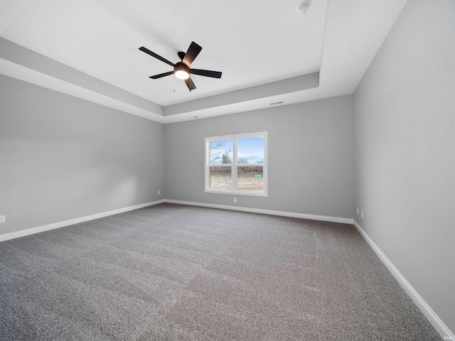 empty room featuring carpet flooring, ceiling fan, and a raised ceiling