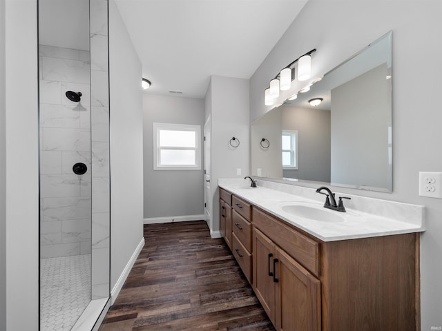 bathroom featuring hardwood / wood-style floors, a wealth of natural light, vanity, and a tile shower