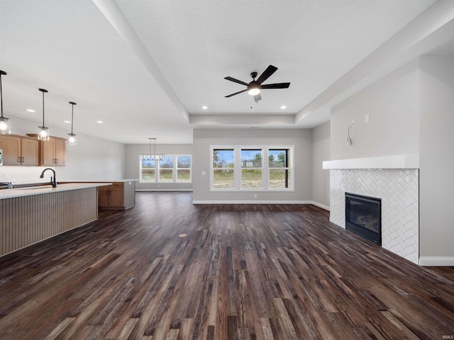 unfurnished living room featuring a fireplace, dark hardwood / wood-style floors, and ceiling fan