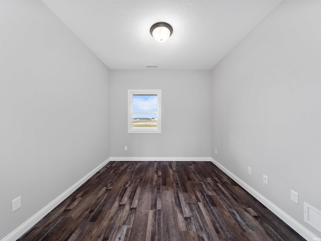 spare room with a textured ceiling and dark hardwood / wood-style floors