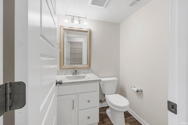 bathroom with toilet, vanity, a textured ceiling, and wood-type flooring