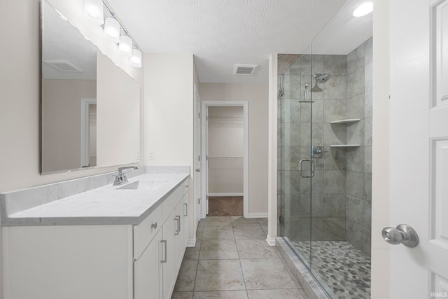 bathroom with walk in shower, tile patterned flooring, vanity, and a textured ceiling