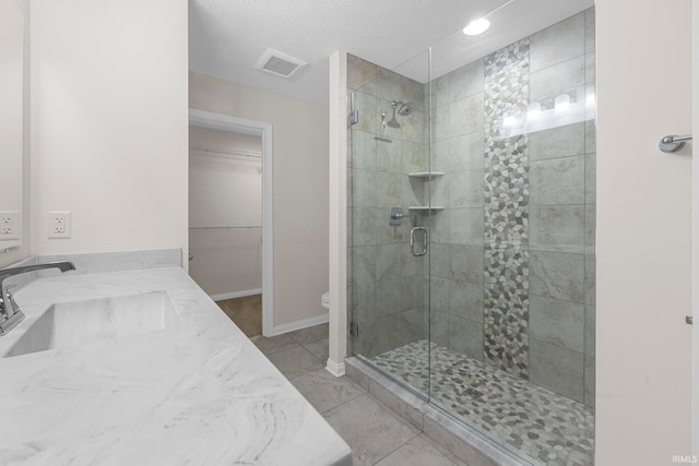 bathroom featuring walk in shower, vanity, toilet, and a textured ceiling