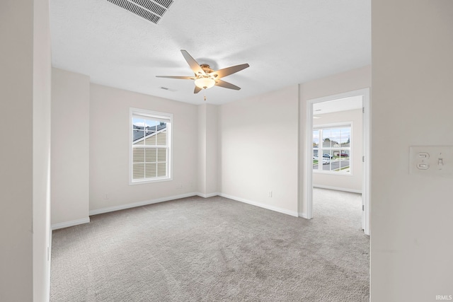 carpeted spare room featuring a healthy amount of sunlight and ceiling fan