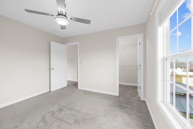 unfurnished bedroom with ceiling fan, multiple windows, a closet, and a walk in closet