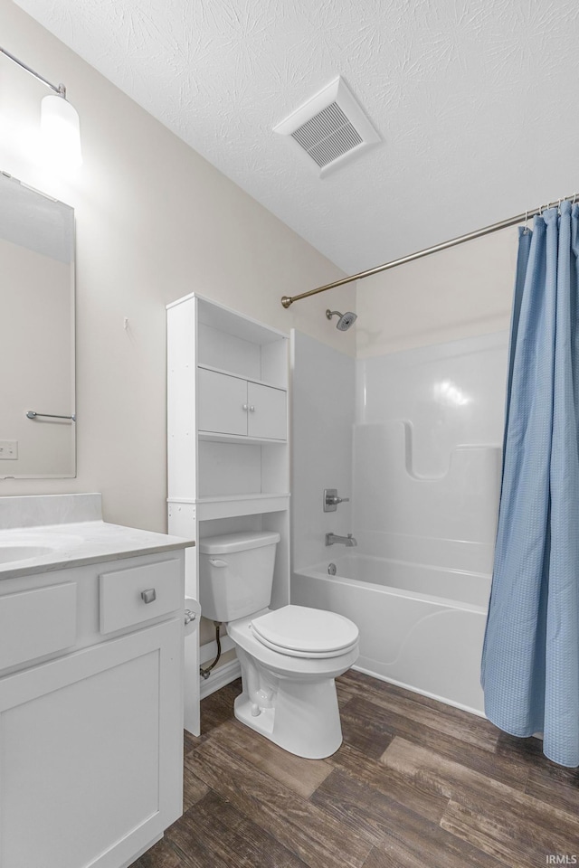 full bathroom featuring shower / bath combo with shower curtain, toilet, hardwood / wood-style floors, a textured ceiling, and vanity