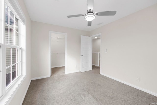 unfurnished bedroom featuring carpet, a spacious closet, and ceiling fan