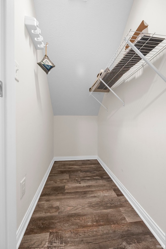 spacious closet featuring dark hardwood / wood-style flooring and vaulted ceiling