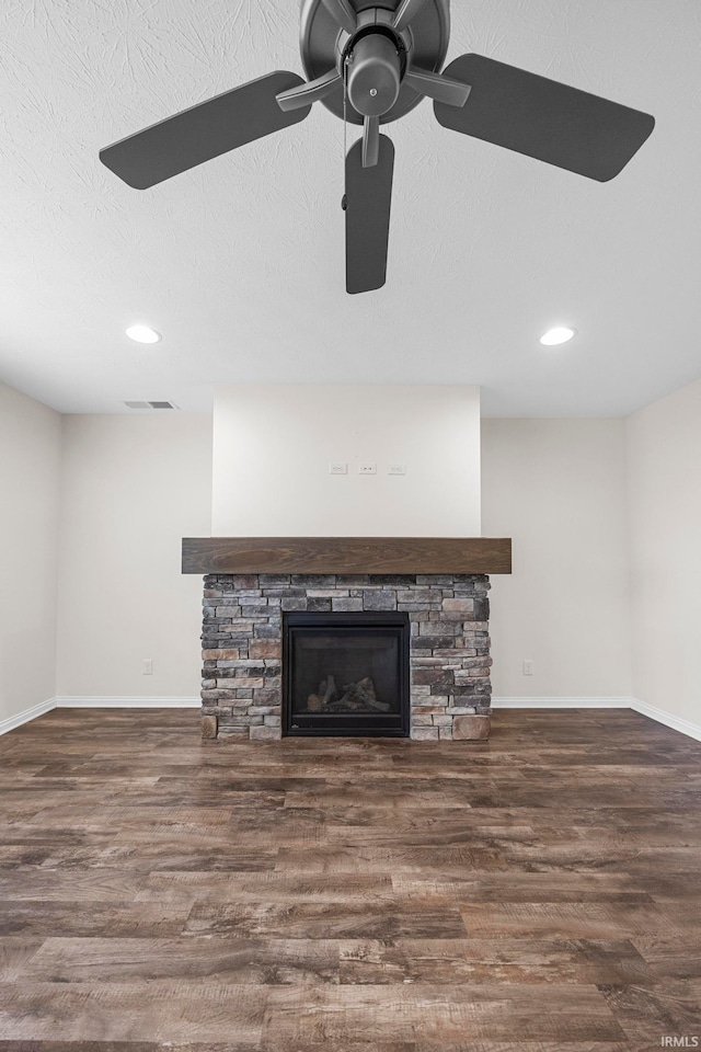 details with a stone fireplace, hardwood / wood-style floors, a textured ceiling, and ceiling fan