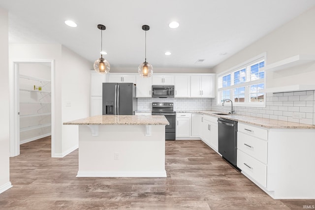 kitchen featuring stainless steel appliances, a kitchen island, light wood-type flooring, sink, and white cabinets