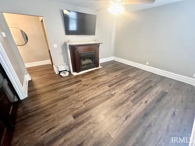 unfurnished living room with dark hardwood / wood-style flooring and ceiling fan