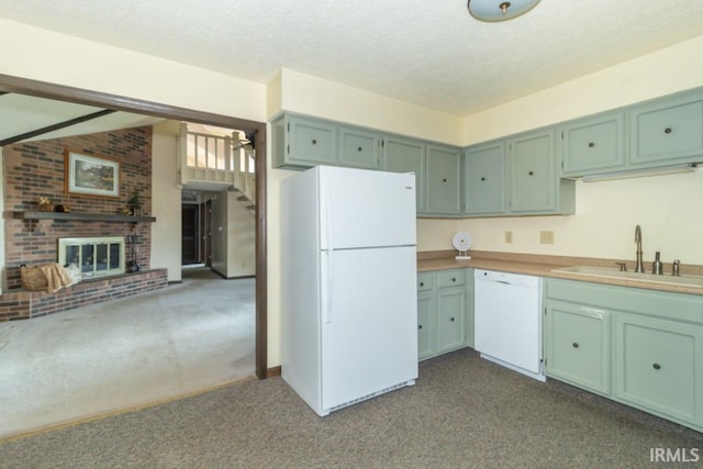 kitchen featuring a fireplace, green cabinets, light carpet, sink, and white appliances