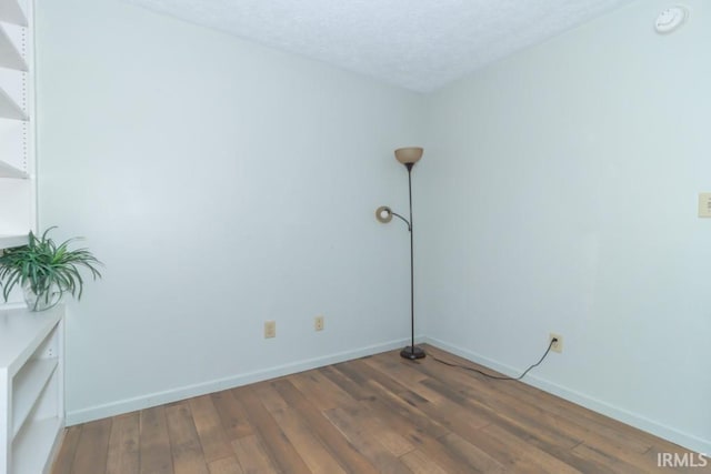 spare room featuring dark wood-type flooring and a textured ceiling