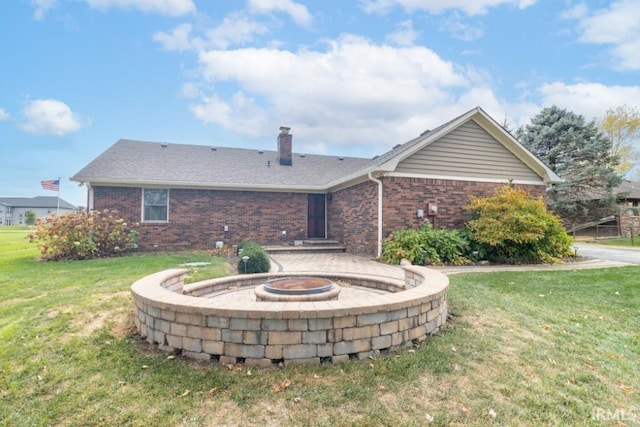 rear view of property featuring a lawn and an outdoor fire pit