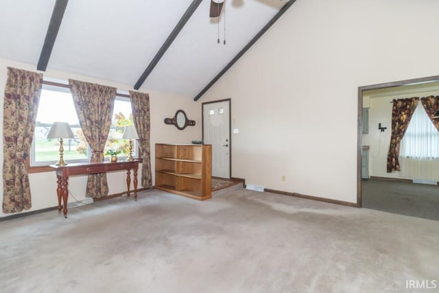 carpeted empty room featuring high vaulted ceiling, plenty of natural light, ceiling fan, and beam ceiling