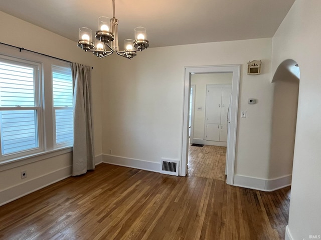 spare room featuring a notable chandelier and dark hardwood / wood-style floors