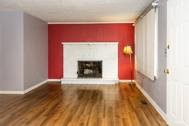 unfurnished living room featuring a fireplace, wood-type flooring, a textured ceiling, and crown molding