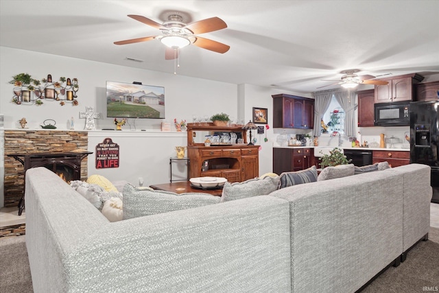 living room featuring carpet flooring, a fireplace, and ceiling fan