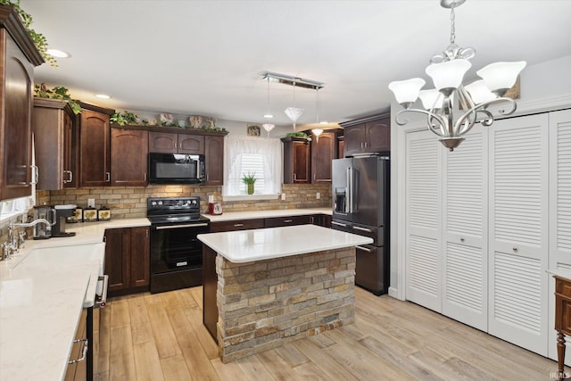 kitchen featuring hanging light fixtures, sink, black appliances, and light wood-type flooring