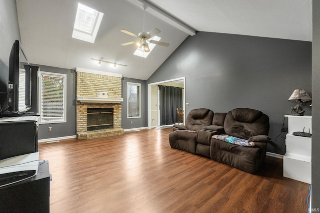 living room featuring hardwood / wood-style floors, ceiling fan, a fireplace, and lofted ceiling with skylight