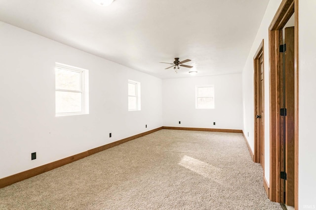 carpeted empty room with a wealth of natural light and ceiling fan