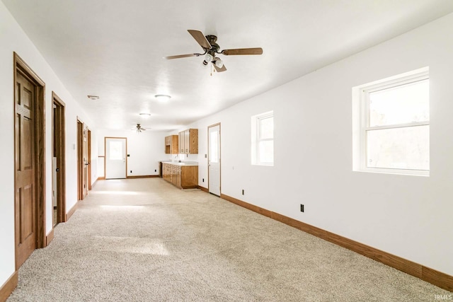 unfurnished living room with light carpet, a healthy amount of sunlight, and ceiling fan