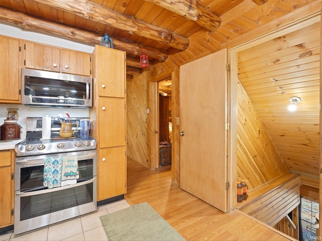 kitchen with stainless steel appliances, light tile patterned floors, beam ceiling, wooden walls, and wooden ceiling