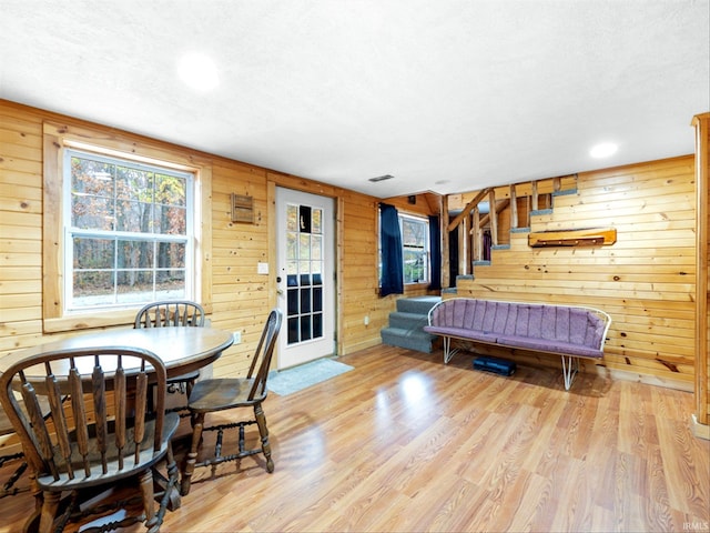 bedroom with wood walls, light wood-type flooring, and a textured ceiling