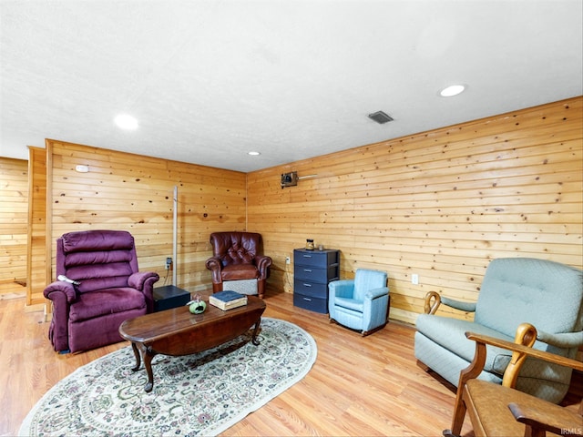 living area featuring light hardwood / wood-style flooring and wooden walls