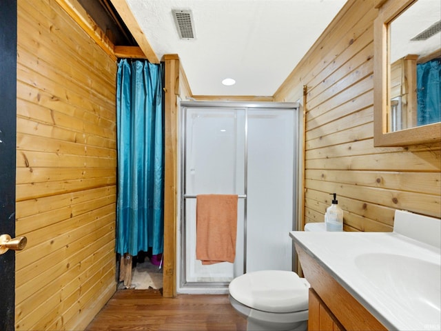 bathroom with wood walls, hardwood / wood-style floors, vanity, an enclosed shower, and toilet