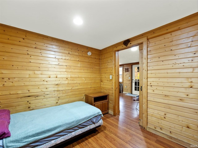 bedroom with wooden walls and light hardwood / wood-style floors