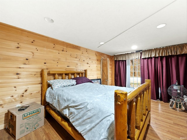 bedroom featuring wood walls and light hardwood / wood-style flooring