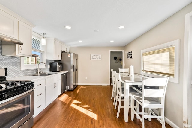 kitchen featuring stainless steel appliances, dark hardwood / wood-style flooring, decorative backsplash, sink, and white cabinets