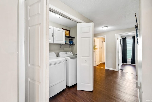 laundry room featuring dark hardwood / wood-style flooring, cabinets, washing machine and clothes dryer, and a textured ceiling