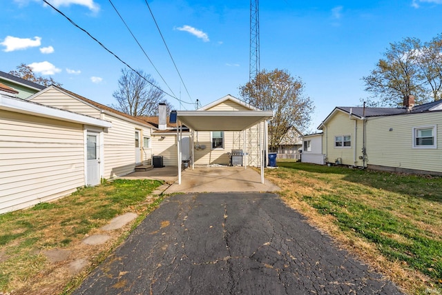 rear view of house featuring central AC unit, a carport, and a yard