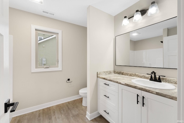 bathroom with hardwood / wood-style flooring, vanity, toilet, and walk in shower