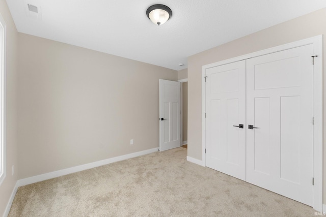 unfurnished bedroom with light carpet and a closet