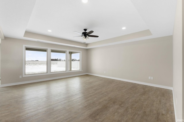 unfurnished room featuring hardwood / wood-style floors, a tray ceiling, and ceiling fan