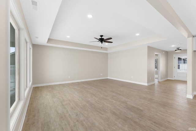 unfurnished living room featuring light wood-type flooring, a raised ceiling, and ceiling fan