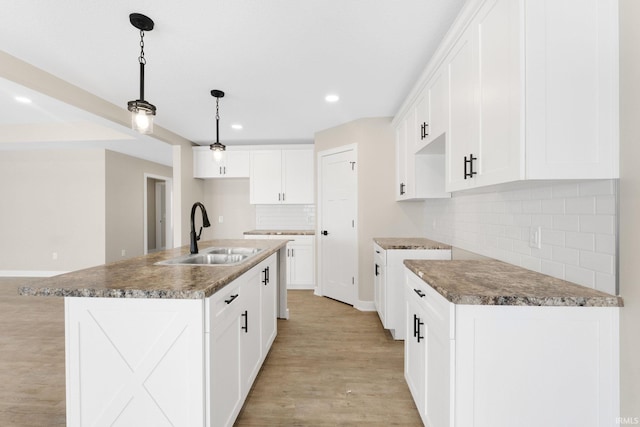 kitchen featuring sink, white cabinetry, and an island with sink