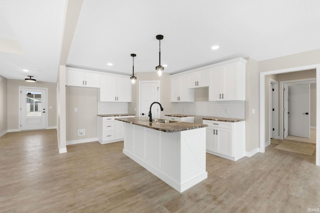 kitchen with a center island with sink, white cabinets, and sink