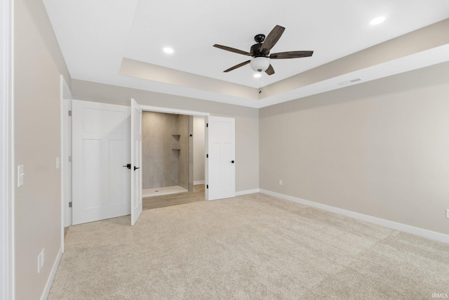 unfurnished bedroom featuring a tray ceiling, ceiling fan, and light colored carpet