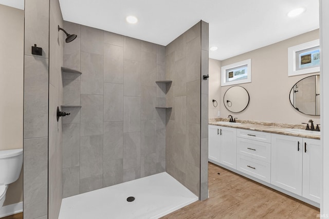 bathroom featuring tiled shower, wood-type flooring, vanity, and toilet