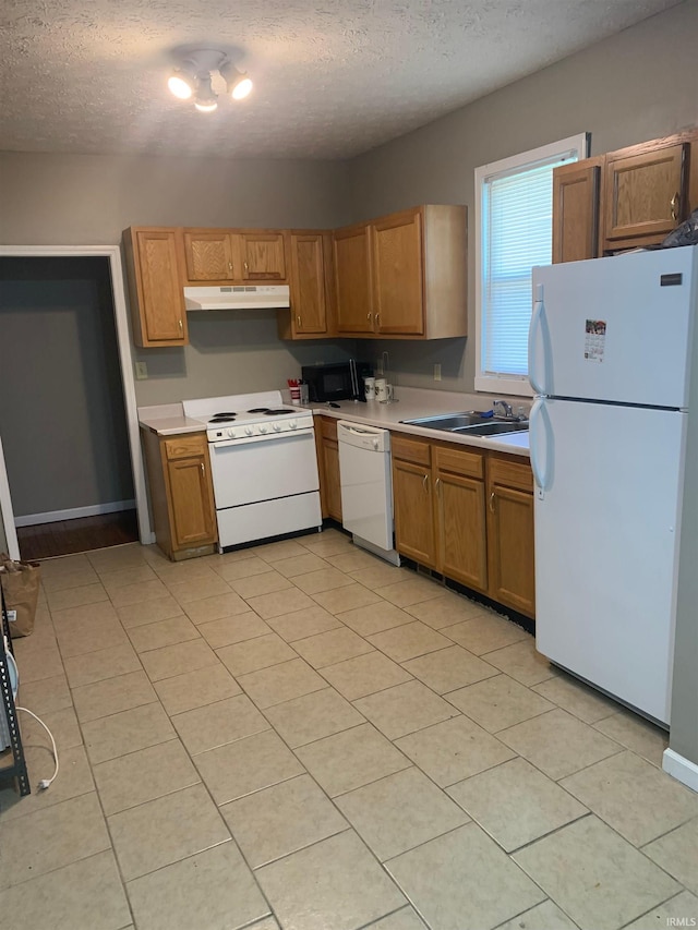 kitchen with a textured ceiling, sink, white appliances, and light tile patterned flooring