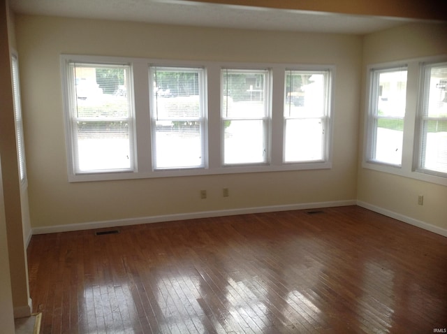 unfurnished room featuring dark hardwood / wood-style floors and plenty of natural light