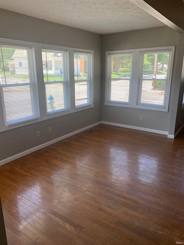 unfurnished room with a textured ceiling and dark hardwood / wood-style floors