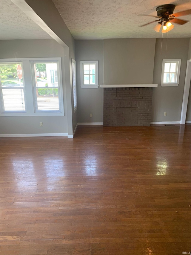 unfurnished living room with ceiling fan, a textured ceiling, and dark hardwood / wood-style floors