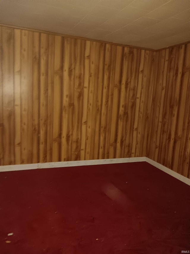 spare room with carpet and wooden walls