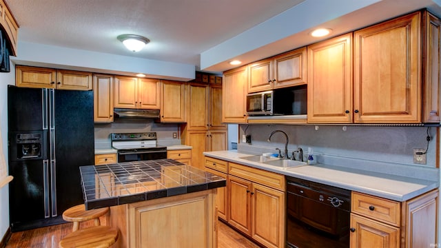 kitchen featuring black appliances, a kitchen island, sink, tile counters, and light hardwood / wood-style flooring